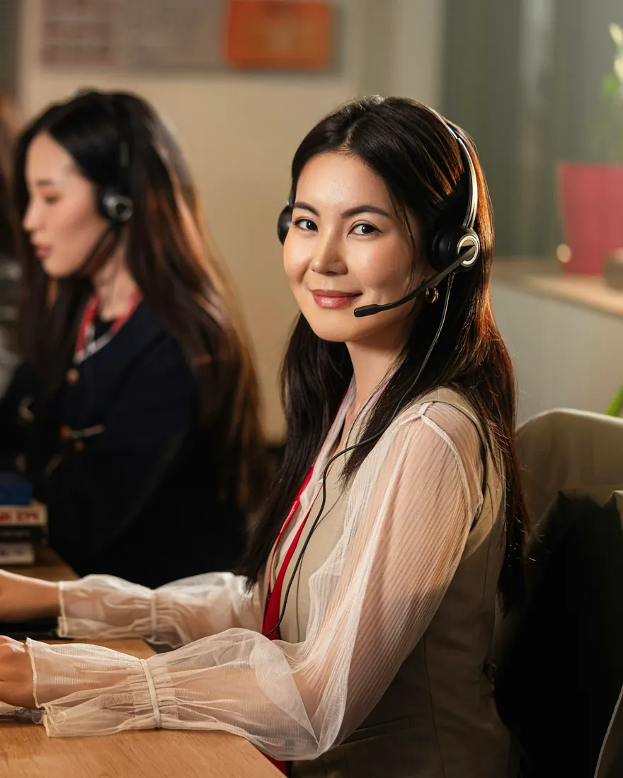 Customer service agent with a headset smiling at her computer